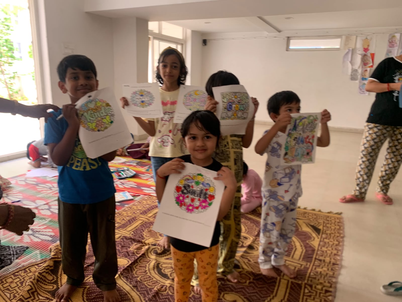 Young children proudly showing mandala artwork with the words Kind, Dream and Grow